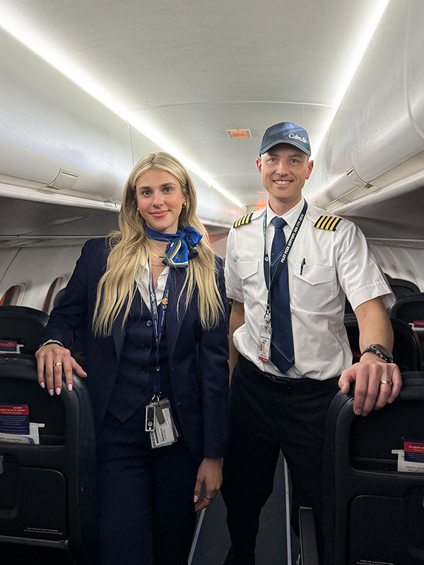 flight attendant and pilot smiling in passenger compartment